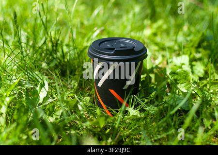 Pappbecher für Kaffee zum Mitnehmen auf grünem Gras Stockfoto