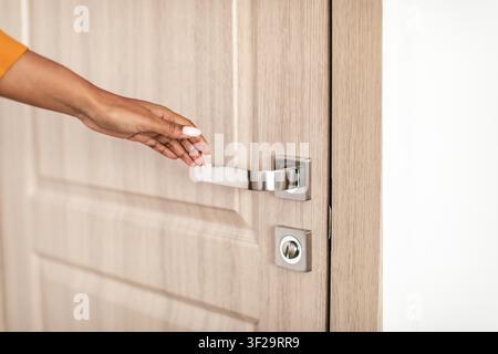 Unerkennbare Frau berührt Türgriff in moderner Büroumgebung, öffnet die Tür Stockfoto