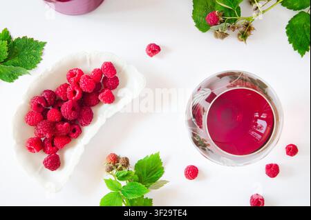 Oberansicht von Himbeeren und einem Glas Rotwein auf weißem Hintergrund Stockfoto