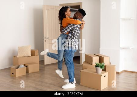 Glückliches junges Paar umarmt sich beim Auspacken im neuen Zuhause, freudiger Moment Stockfoto