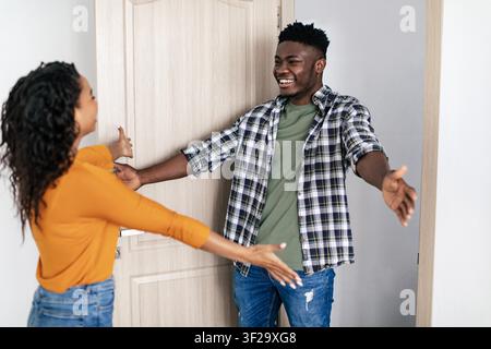Fröhlicher afroamerikanischer Mann umarmt eine weibliche Freundin an der Haustür, Freundschaftskonzept Stockfoto