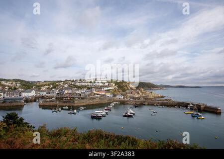 Erhöhte Weitwinkelansicht des Hafens und Küstendorfes Mevagissey unter einem bewölkten Himmel, zeigt die Steinquaimauern, festgemachte Boote und Häuser, Cornwall, UK. Stockfoto