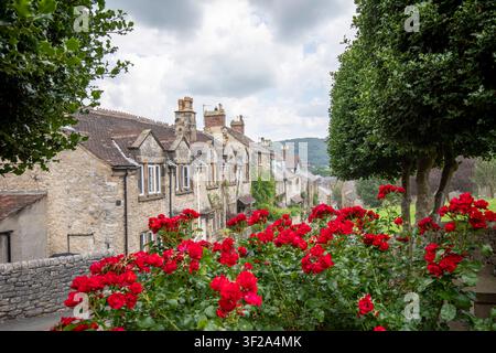 Eine malerische Reihe traditioneller Steinhäuschen auf einem steilen Hügel entlang der North Church Street, gesehen von einem grasbewachsenen Ufer in Bakewell, Derbyshire, UK. Stockfoto