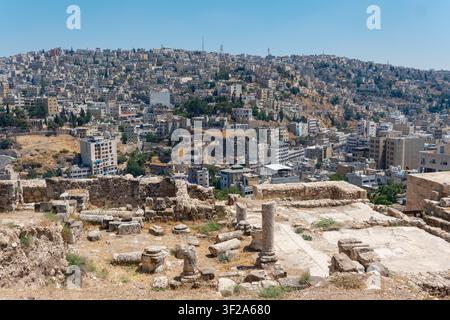 Blick auf die historischen Ruinen der Zitadelle von Amman mit Steinsäulen und antiken Mauern, die die dichte städtische Landschaft von Amman, Gouvernement Amman, Jordanien, überblicken Stockfoto