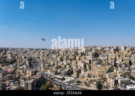 Blick auf den Raghadan-Flaggenmast, der über der dichten städtischen Landschaft aus beigen Steinbauten in Amman, Gouvernement Amman, Jordanien, aufragt. Stockfoto