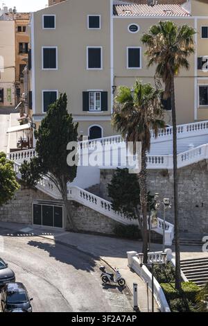 Ansicht einer weißen Steintreppe mit kunstvollen Geländern, die zu einem historischen Gebäude in Mao, Balearen, Spanien führt. Stockfoto