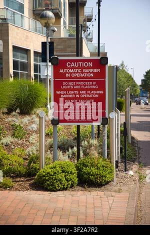 Ein rotes Warnschild mit der Aufschrift "Vorsicht Automatischer Schrankenbetrieb" mit Anweisungen auf Ziegelpflaster in Salford Quays, Salford, Manchester, UK. Stockfoto
