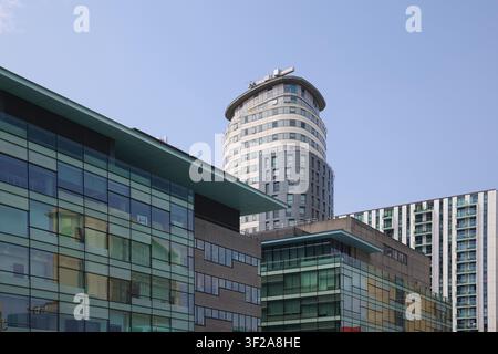 Eine Bodennah-Aufnahme von zeitgenössischen Hochhauswohnungen und Bürogebäuden vor einem blauen Himmel in Salford Quays, Manchester, UK. Stockfoto