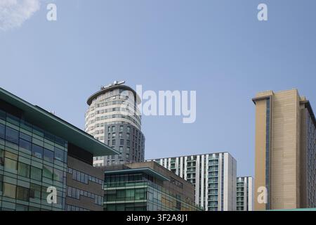 Eine Bodennah-Aufnahme von zeitgenössischen Hochhauswohnungen und Bürogebäuden vor einem blauen Himmel in Salford Quays, Manchester, UK. Stockfoto