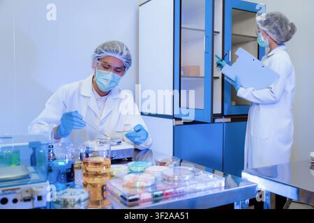 Asiatisches Forschungsteam arbeitet an biotechnologischen Pharmazeutforschungen, Chemiker wiegt pharmazeutische Zutat auf einer Digitalwaage und überprüft medizinisches Ca Stockfoto