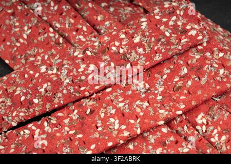 Rote-Bete-Kracker-Stücke, zerbröseltes dünnes Brot aus Rote-Bete-Ruske, zerbrochenes rotes Diät-Vollkornknäckebrötchen, verschiedene Samen-Vollkornknäckebrot, langes Knäckebrot Stockfoto