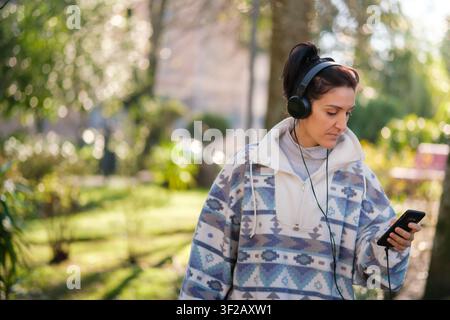Frau hört Musik mit Kopfhörern und Smartphone im Freien Stockfoto