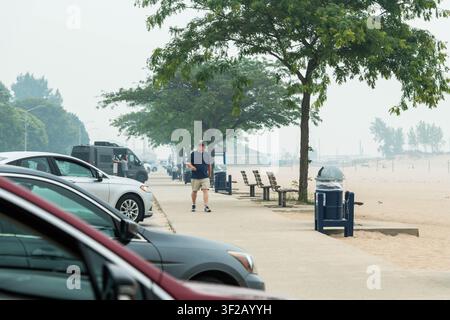LUDINGTON, MICHIGAN, USA - 17. Jul 2026. Ein Mann geht den Strandweg im Stearns Park entlang, während dichter Waldbrandrauch aus Ontario, Kanada, die Sicht entlang der Ufer von Lake Michigan in Ludington auf einen Bruchteil des Normalzustands reduziert. Die rauchigen Bedingungen haben seit mehreren Tagen angehalten. Credit: Jeffrey Wickett/Alamy Live News Stockfoto
