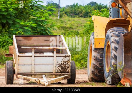 Anhänger, der neben einem Frontlader auf einer kleinen Farm in Brasilien geparkt ist. Ehrlich gesagt ist das hier eine normale Szene. Stockfoto