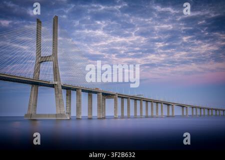 Ein atemberaubender Sonnenuntergangsblick auf die ikonische Vasco-da-Gama-Hohlkastenbrücke, die sich über den weiten Tejo in Lissabon, Portugal, erstreckt Stockfoto
