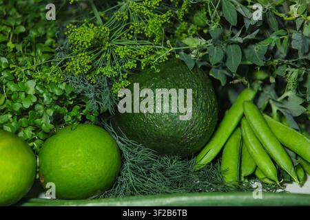 Eine Nahaufnahme von frischem biologischem Grünzeug und Kräutern, darunter Avocado, Limette, Zuckererbsen und Dill, die ein dichtes und gesundes vegetarisches Gericht bilden Stockfoto