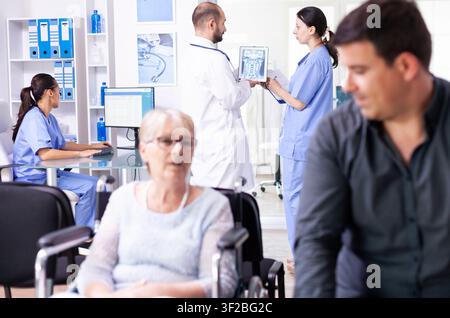 Arzt und Krankenschwester überprüfen eine Patienten-Röntgenaufnahme auf einem Tablet, während sie mit einer Krankenschwester im Krankenhausflur diskutieren, Arzt trägt weißen Kittel und Stethoskop, Gesundheitssystem medizinische Diagnose Krankheit Teamarbeit. Stockfoto