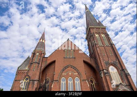 Backsteinkirche mit zwei Türmen unter einem blauen Himmel mit vereinzelten Wolken. Architekturmerkmal der First Baptist Church. Stockfoto