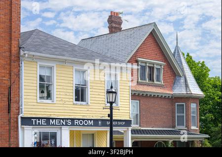 Historische Straßenansicht mit einem gelben Schindel-Friseursalon neben einem viktorianischen Backsteingebäude. Stockfoto