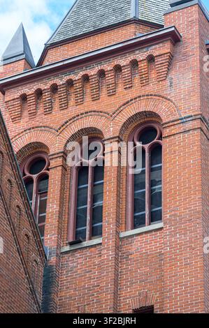 Historischer Kirchturm mit gewölbten Fenstern, dekorativer Mauerarbeit und verwitterten architektonischen Details. Port Hope United Church. Stockfoto