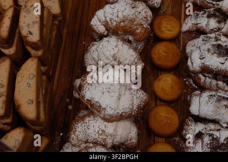 Goldbraune Gebäckstücke, die mit Puderzucker bestäubt sind, ruhen auf einem Holzbrett. Süße Leckereien präsentieren sich warm. Ideal für Café-Menüs, Food-Blogs Stockfoto