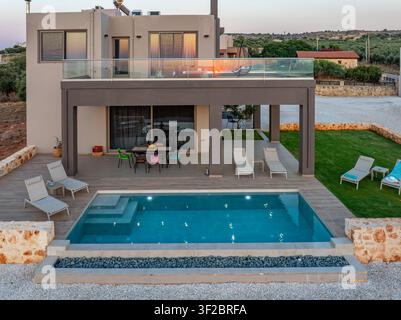 Luftaufnahme einer modernen Villa mit einem privaten Schwimmbad, Sonnenliegen auf einem Holzdeck und einem Terrassenbereich in Chania, Griechenland. Stockfoto