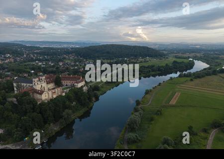 Luftaufnahme der Abtei Tyniec auf einer Klippe mit Blick auf die Weichsel, umgeben von üppiger Vegetation und ländlichen Landschaften unter einem sanften Abendhimmel in Kra Stockfoto