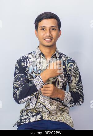 Freundlicher junger Asiate lächelt und schaut in die Kamera, isoliert auf Studiohintergrund Stockfoto
