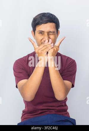 Ausdrucksvoller Asiate, der seine Wangen mit einer verspielten überraschten Geste berührt, isoliert auf blauem Hintergrund. Stockfoto