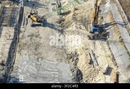 Luftaufnahme einer Baustelle mit einem großen Raupenkran und einem gelben Bagger, die auf einem Erdaushubgebiet in Istanbul, Istanbul, Tur arbeiten Stockfoto