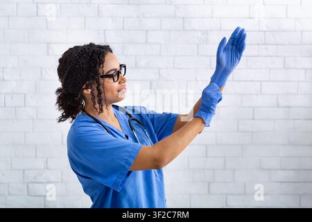 Afroamerikanische Veterinärmedizinerin, die Schutzhandschuhe in der Tierklinik anlegt Stockfoto