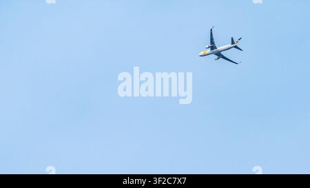 Breites horizontales Foto eines Passagierflugzeugs, das hoch über Mainz, Deutschland, vor einem klaren blauen Himmel fliegt. Das Verkehrsflugzeug befindet sich in der oberen rechten Ecke Stockfoto