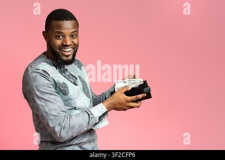 Aufgeregter afroamerikanischer Mann, der Geld in die Brieftasche legt Stockfoto