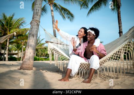 Vielfältige Content-Creator-Paare Vlogging oder Streaming von einem malerischen tropischen Strand im Sommerurlaub Stockfoto