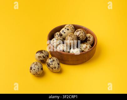 Wachtel-Eier, Diät-Ei in Holzschüssel, Gesunde Frühstücksoption, Natürliche organische Ernährung, Salat-Zutat Geflecktes Wachtel-Ei auf gelbem Hintergrund Stockfoto