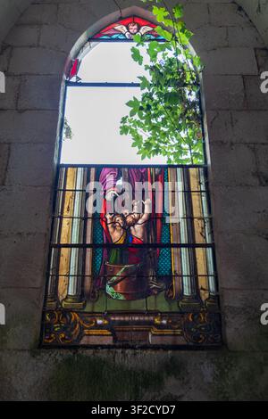 Niedrigwinkelansicht eines zerbrochenen Buntglasfensters in den historischen Steinruinen der verlassenen Chapelle de Beaulieu Stockfoto