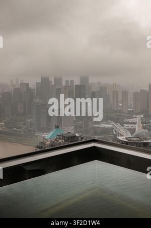 Chongqing, China - 8. Jun 2026 - Von der minimalistischen Kante eines Hochgebirgspools aus blickend, zeigt diese vertikale Komposition die Dichte von Chongqing Stockfoto