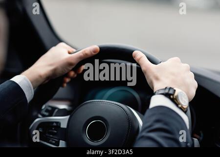 Unerkennbarer Geschäftsmann, der allein in seinem neuen Auto fährt Stockfoto
