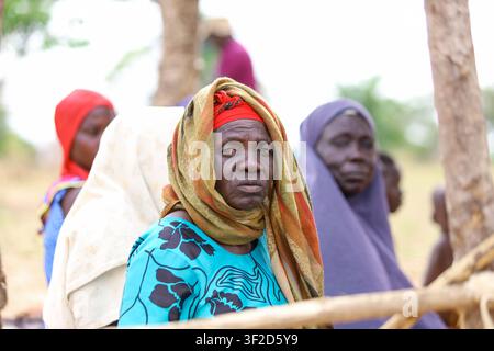 Porträt einer älteren afrikanischen Frau, die ein farbenfrohes Kopftuch und ein traditionelles Kleid trägt, sitzt in einer einfachen, holzkonstruierten Moschee Stockfoto