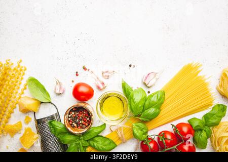Hintergrund Pasta. Verschiedene Arten von trockener Pasta mit Gemüse und Kräutern auf weißem Hintergrund. Freier Platz für Text. Draufsicht Stockfoto