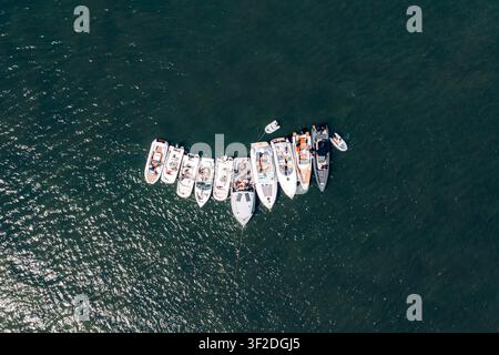 Poole, England, Vereinigtes Königreich - 10. Juli 2021: Luftaufnahme einer Gruppe von Motorbooten, die im ruhigen dunklen Wasser des Hafens aneinander festgemacht sind. Stockfoto