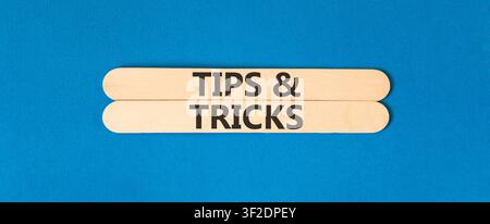Symbol für Tipps und Tricks. Konzeptwörter Tipps und Tricks auf schönen Holzstäben. Wunderschöner blauer Hintergrund. Geschäftliche Tipps und Tricks Motivation Stockfoto