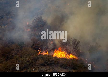 Luftaufnahme eines Waldbrandes, der durch Bäume brennt, mit dichtem Rauch, der über den Hügel in Chianocco, Piemont, Italien aufsteigt Stockfoto