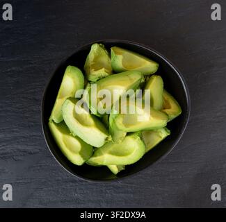 Viele Hass-Avocado-Scheiben in einer Schüssel, braune Avocado-Schnitte, frische Alligatorbirnenstücke, Blick von oben Stockfoto