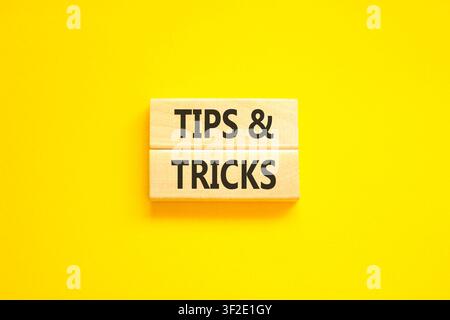 Symbol für Tipps und Tricks. Konzeptwörter Tipps und Tricks auf schönen Holzblöcken. Schöner gelber Hintergrund. Geschäftliche Tipps und Tricks motivieren Stockfoto