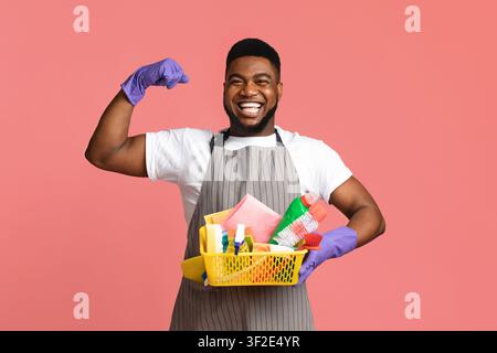 Mister Muscle. Schöner Schwarzer Mann Mit Vielen Waschmitteln In Den Händen, Zeigt Bizeps, Posiert Über Rosa Studio Hintergrund Mit Copy Space Stockfoto