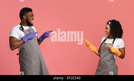Fröhliche Afrikanischen Paar In Schürzen Und Gummihandschuhe Zeigen Sich Gegenseitig Stockfoto