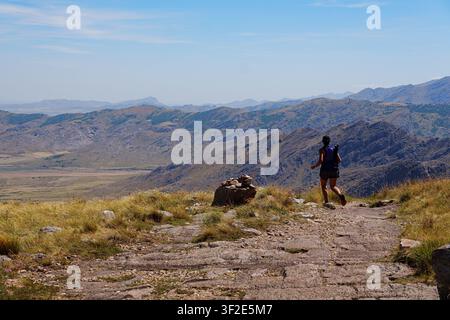 Traillauferin rennt in Richtung Horizont mit einem malerischen trockenen Bergblick Stockfoto