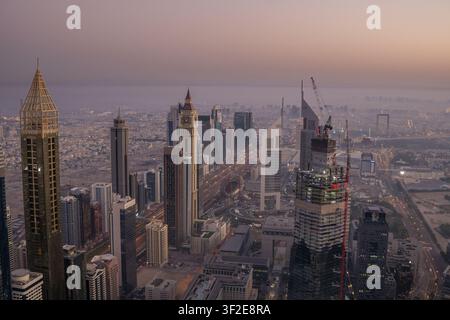 Luftbild der Skyline von Dubai entlang der Sheikh-Zayed-Straße bei Sonnenuntergang, mit Hochhäusern, Baukränen und urbaner Infrastruktur in Dubai, Dub Stockfoto