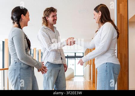Eine Gruppe von Schülern genießt eine Pause zwischen den Unterrichtsstunden, führt ungezwungene Gespräche und gibt sich die Hand in einer hellen, modernen Bildungseinrichtung. Stockfoto